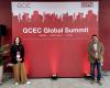 Farah and Mazhar stand in front of the GCEC Global Summit backdrop